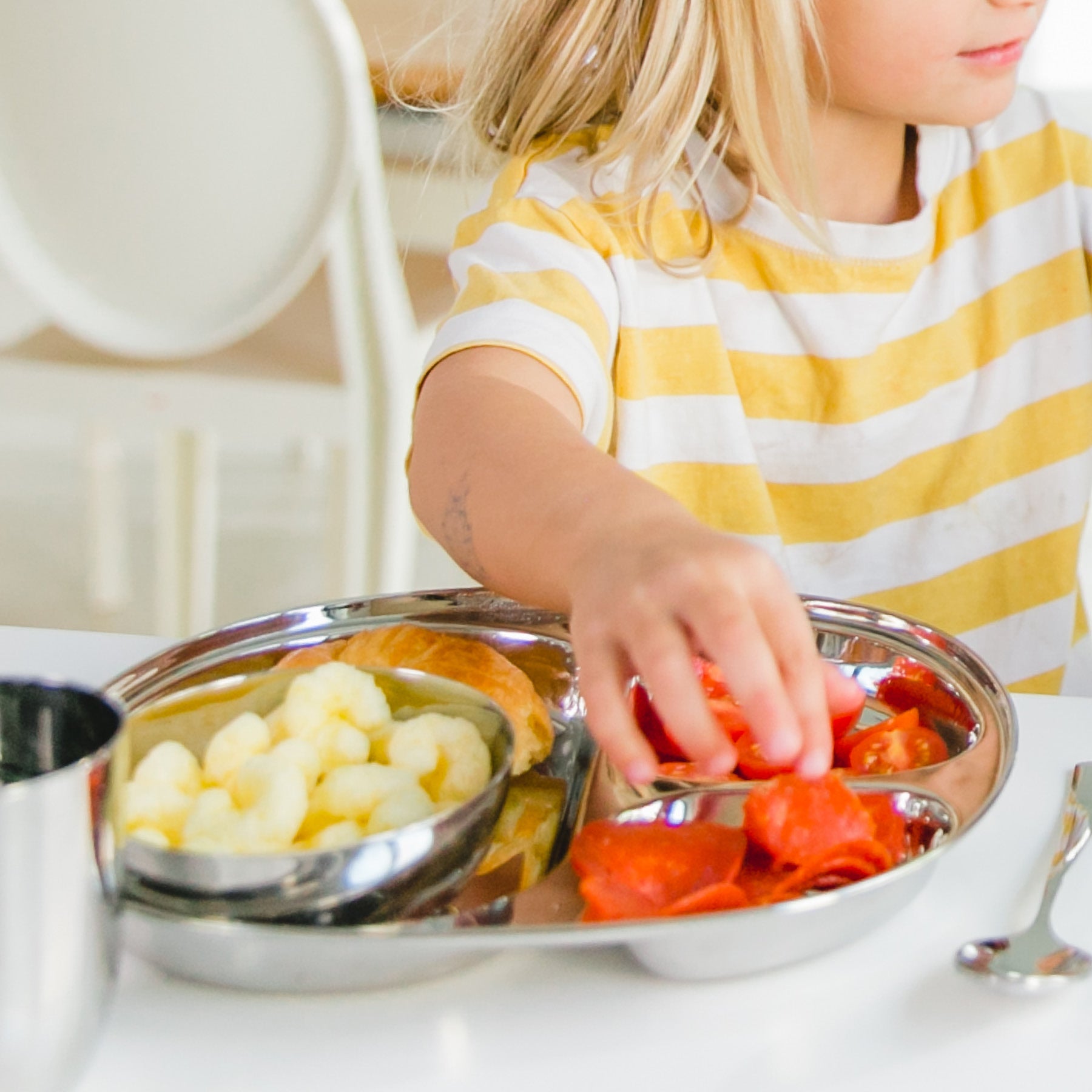 child eating from stainless dish plate